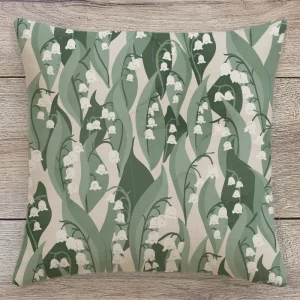 Lily of the Valley ogee cushion in green and neutral tones on a wooden table background – modern botanical interior from the Flow Collection by Eldy Pattern Design.